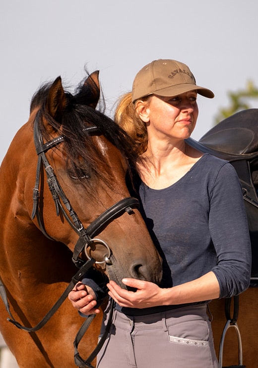 Tanja steht neben einem braunen Pferd